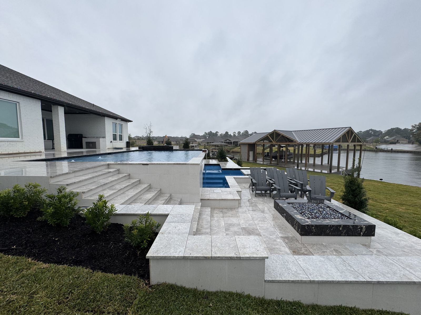 Infinity-edge lakefront pool with steps and fire pit