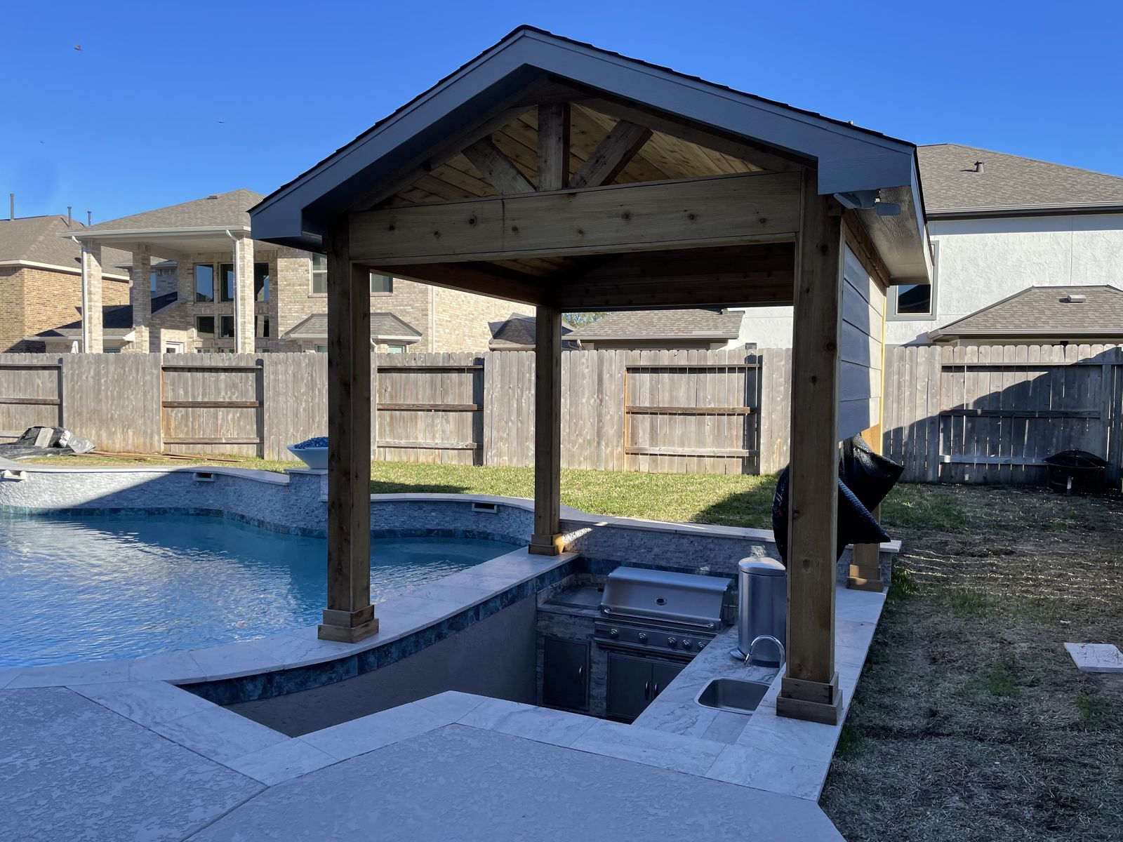 Cedar pergola over a sunken outdoor kitchen by the pool