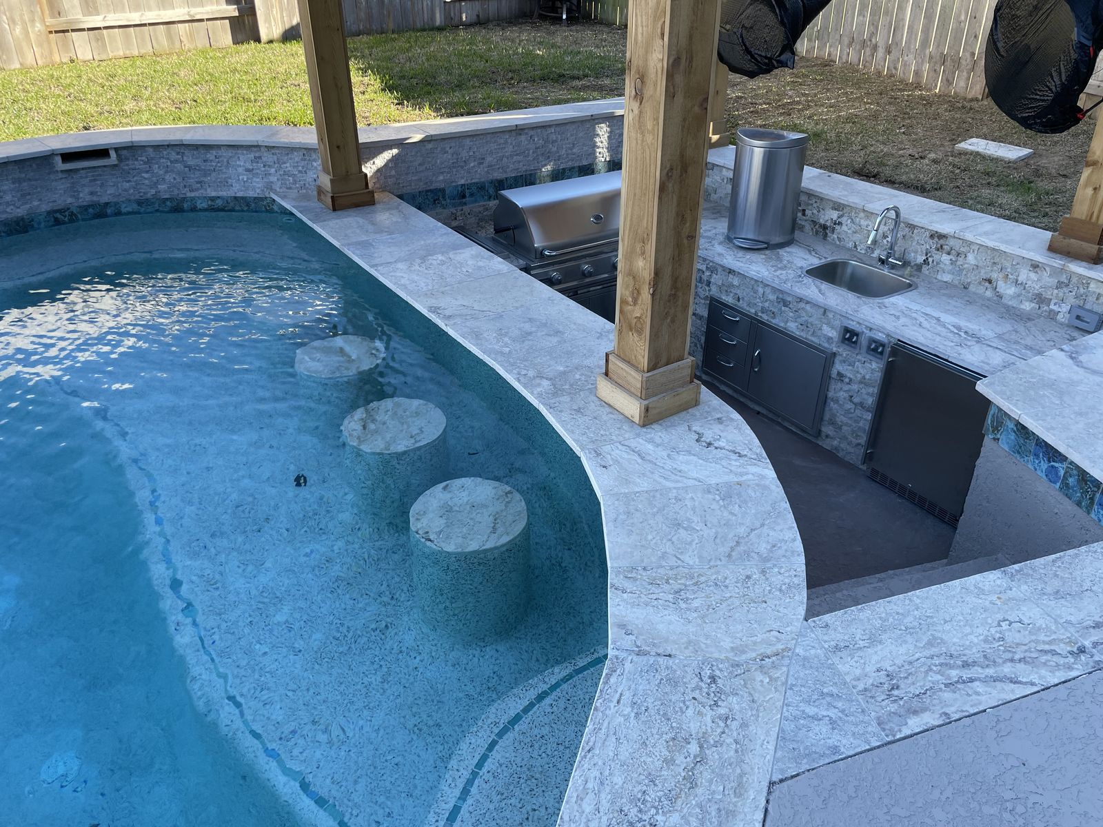 Swim-up bar stools beside an outdoor kitchen